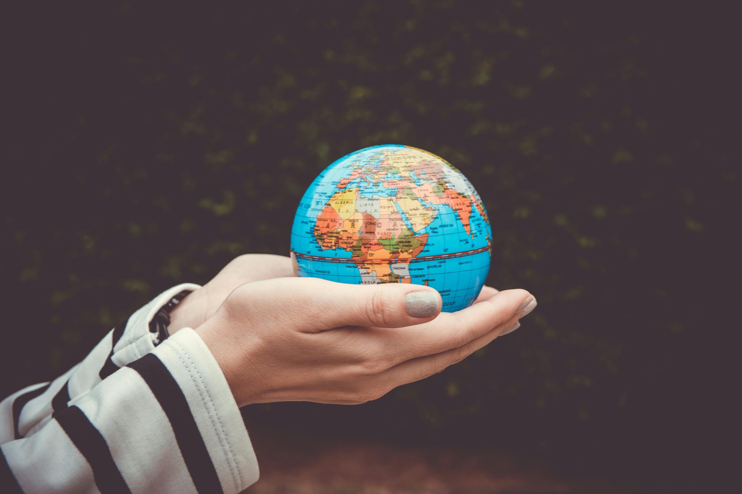 Person holding a small globe in hands, showcasing Earth. Ideal for global concepts or travel themes.